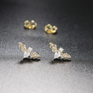 Macro shot of gold-plated bat stud earrings with sparkling cubic zirconia inlay