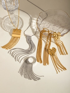 Detailed view of long metal tassel earrings in gold and silver finish with heart pendants