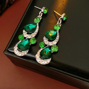 Detailed macro shot of vintage style teardrop earrings with green crystals on black leather
