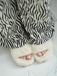 Close-up of white plush open-toe slippers paired with stylish zebra pattern pajama pants