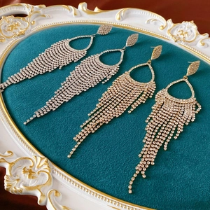 Luxurious silver and gold tassel earrings with full diamond pavé on velvet display
