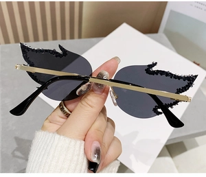 Detailed close-up of flame shaped sunglasses with rhinestones and golden metal temples