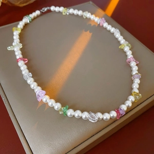 Detail of minimalist pearl necklace with colorful translucent gravel on leather case