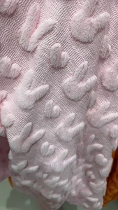 Close-up of pink plush pillowcase with textured rabbit pattern and soft knit fabric