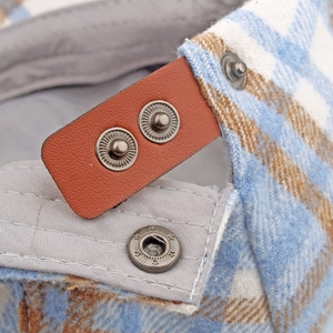 Close-up of plaid wool newsboy hat with leather adjustment strap and star metal snaps