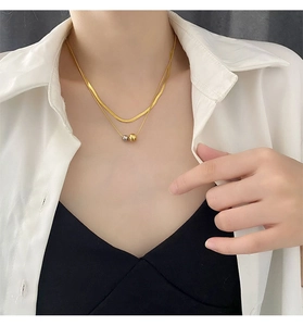 Detail of layered gold snake chain and minimalist bi-color beads on model neck
