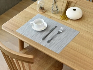 Detailed close-up of grey woven PVC placemat texture on a modern wooden table