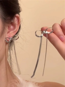 Close-up of silver bow tassel earrings featuring long chain fringe on female model