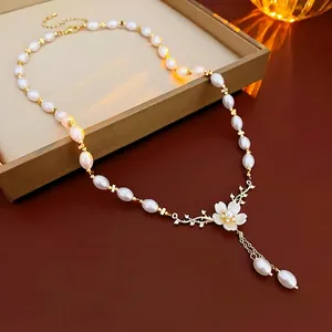 Collier fleur doré élégant avec perles et pompons sur un coffret à bijoux chic