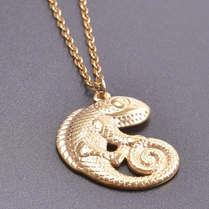 Detailed close-up of 18k gold lizard pendant with intricate scale textures on black