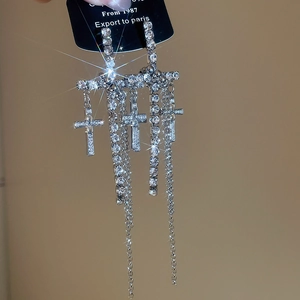 Macro shot of silver cross tassel earrings with sparkling rhinestones in a starry effect