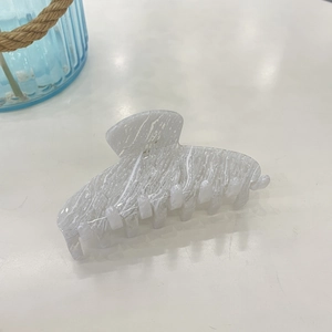 Close-up of white marble texture acetate hair claw clip with elegant curved design