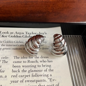Macro view of silver geometric spiral earrings placed on a fashion magazine page