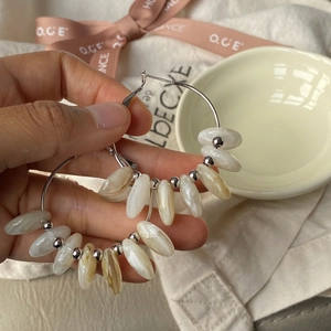 Detail of silver hoop earrings with marble texture resin beads on a cream fabric background