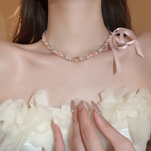 Détail d'un collier ras du cou en perles d'eau douce avec un nœud en satin rose