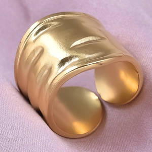 Detailed view of wide gold 304 stainless steel ring with hammered texture on purple silk