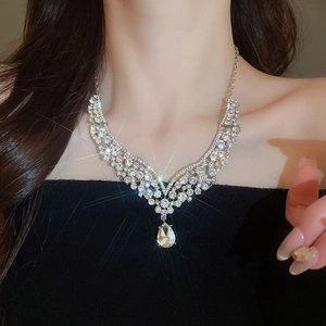 Close-up of silver V-shaped necklace with pear-cut diamond pendant on model's neck