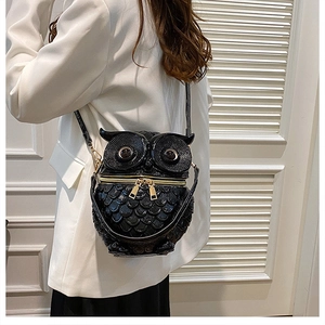 Detail of owl-shaped crossbody bag with feather embossed texture and gold zippers