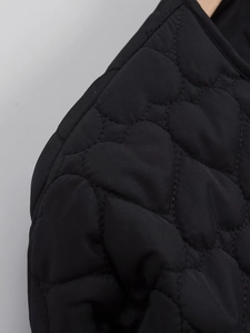 Detail of heart-shaped quilting patterns on black jacket showing high texture and padding