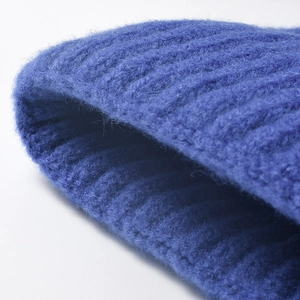 Close-up macro view of cobalt blue thick ribbed knit warm winter beanie hat texture