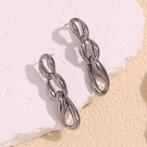 Detail shot of silver chunky three-link chain earrings on a minimalist stone surface