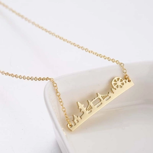 Golden skyline necklace with ferris wheel pendant on a minimalist white tray