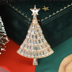 Close-up of golden Christmas tree brooch with rhinestones on green velvet box