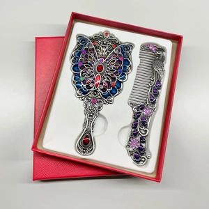 Close-up of vintage butterfly mirror and peacock comb set with colorful enamel inlay