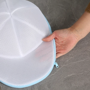 Detail of white mesh laundry bag showing fine fabric texture and blue zipper closure