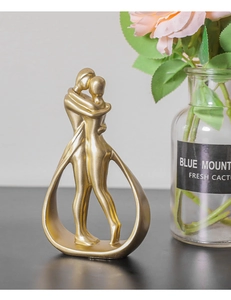 Dettaglio della scultura astratta di coppia che si abbraccia in oro opaco per casa