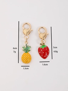 Detail view of strawberry and pineapple fruit keychains with size measurements in cm