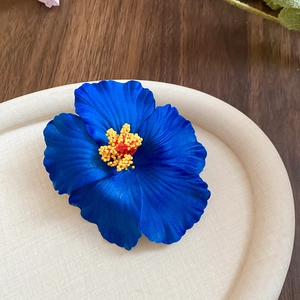 Macro shot of dark blue acrylic hibiscus hair clip with realistic silk texture petals