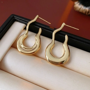 Close-up of gold irregular wavy earrings presented in a luxury satin-lined jewelry box