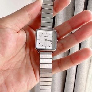 Detailed close-up of a silver square quartz watch with a brushed metal link bracelet