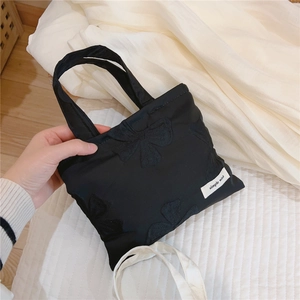 Close-up of black satin handbag with elegant butterfly embroidery and simple wish label