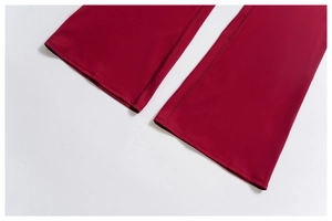 Close-up of double-stitched hem on burgundy high-waisted flared sports trousers