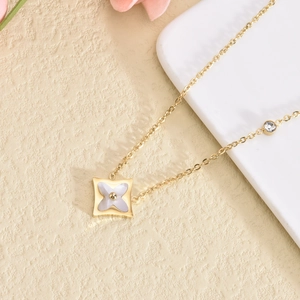 Detailed close-up of golden necklace with a white flower pendant and sparkling zircon