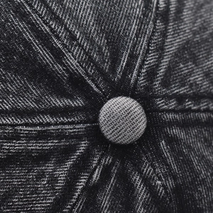 Macro shot of stitched seams and top button detail on washed denim baseball cap