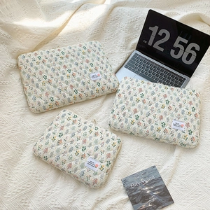 Three sizes of floral quilted laptop sleeves in off-white fabric on a textured background