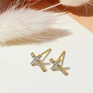 Macro shot of gold cross stud earrings with sparkling pavé zircons on a white display