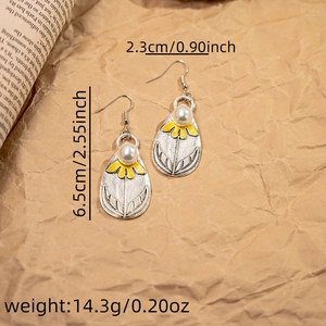 Detail view of silver earrings with yellow flower petals, white pearls and size dimensions