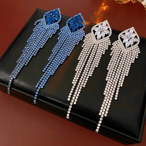 Detail of luxury rhombic long fringe earrings with blue and silver zircons on leather