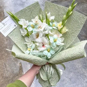 Handheld bouquet with white gladiolus wrapped in green textured stone pattern paper