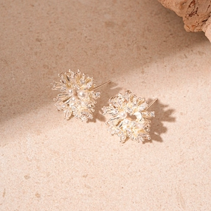 Orecchini a fiore con zirconi e perla centrale su sfondo in pietra dal design sobrio