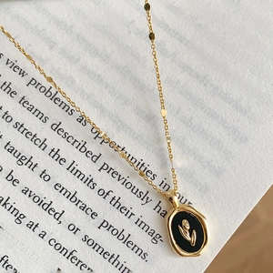 Macro shot of a gold necklace with a black oval floral pendant on a book page