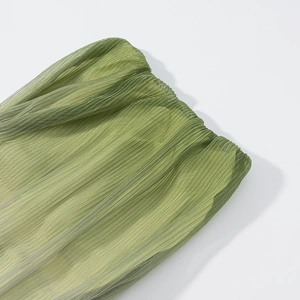 Detail of green gradient pleated fabric with vertical texture and subtle glossy finish