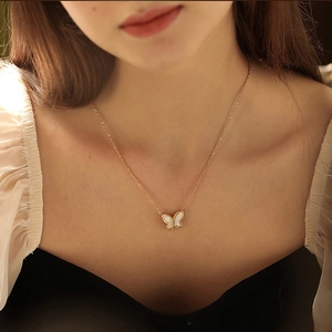 Golden butterfly necklace with white mother of pearl pendant worn on model's neck