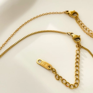 Macro detail of 18K gold plated lobster clasp and adjustable chain with K18 engraving