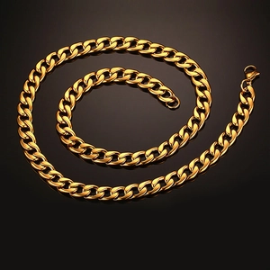 Polished gold curb link bracelet in stainless steel with lobster clasp on black background