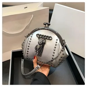 Detail of silver studded shell bag with rhinestone bear charm and metal fringe
